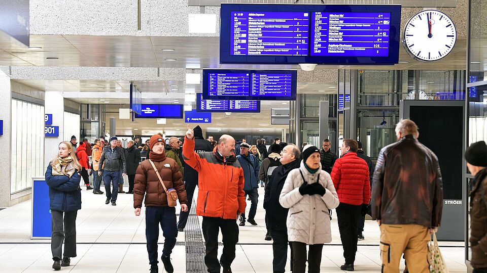 Menschen laufen im Untergrund des Augsburger Hauptbahnhofs. An der Decke sind mehrere Anzeigetafeln. Ein Klick sorgt für eine Großansicht des Bildes.
