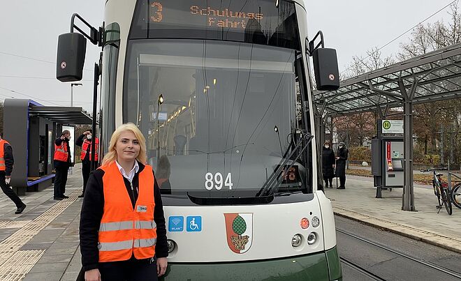 Frau steht in Warnweste vor einer Straßenbahn
